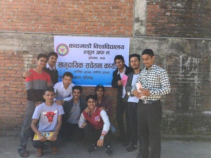 A group of young men posing beneath a Kathmandu University School of Law banner.